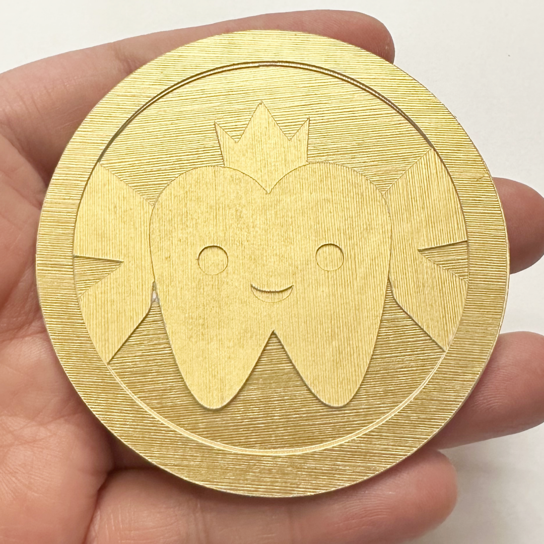 Gold coin with a tooth design held in a hand against a white background