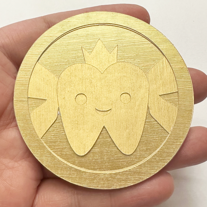 Gold coin with a tooth design held in a hand against a white background