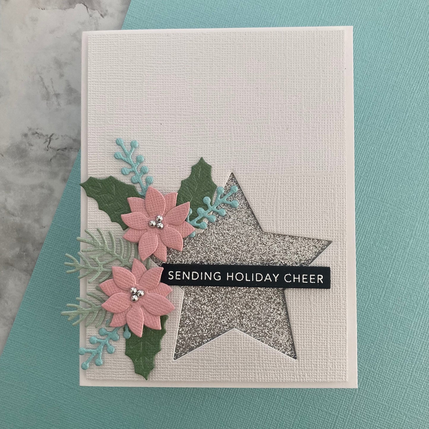 Handmade christmas card with flowers and star design on a textured cardstock.